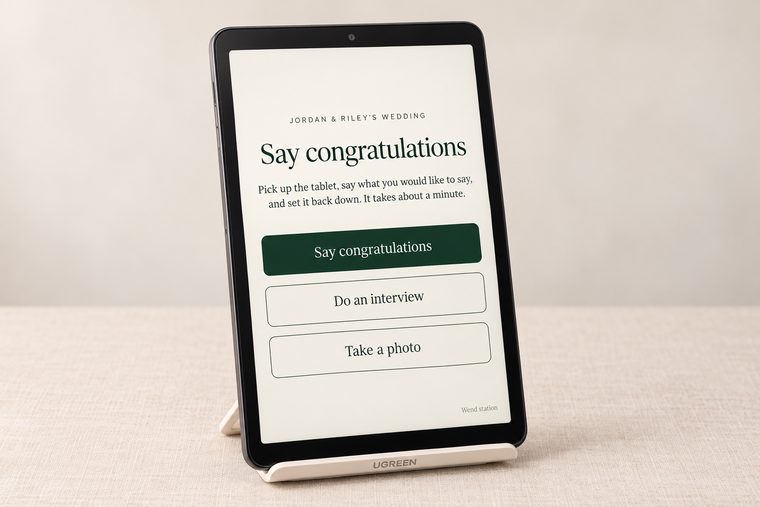 A tablet station on its stand. The screen reads Say congratulations, with buttons for Say congratulations, Do an interview, and Take a photo